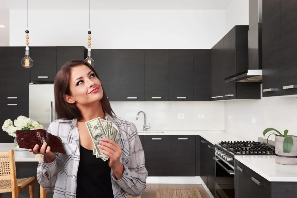 happy woman holding dollars and wallet thinking of kitchen renovation